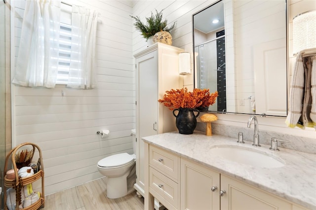 bathroom featuring walk in shower, toilet, wood walls, vanity, and hardwood / wood-style flooring