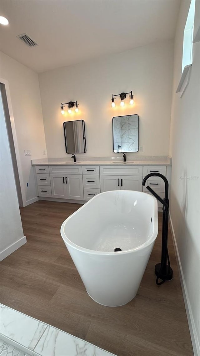 bathroom featuring vanity, a bath, and wood-type flooring