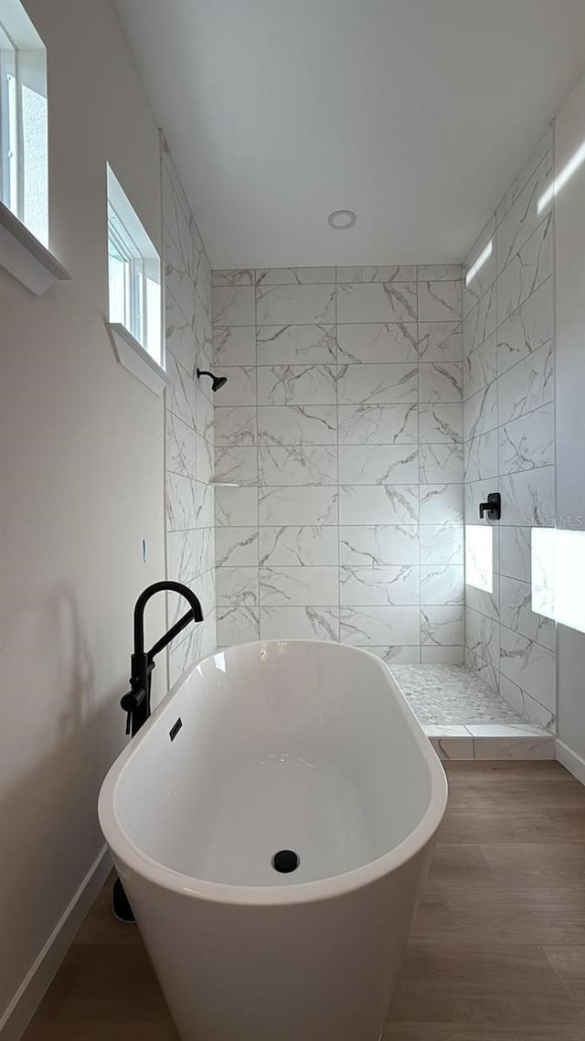 bathroom featuring hardwood / wood-style flooring, plus walk in shower, and tile walls