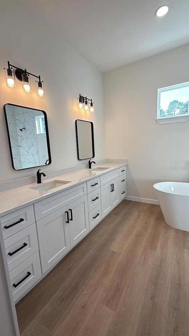 bathroom featuring hardwood / wood-style flooring, vanity, and a bath