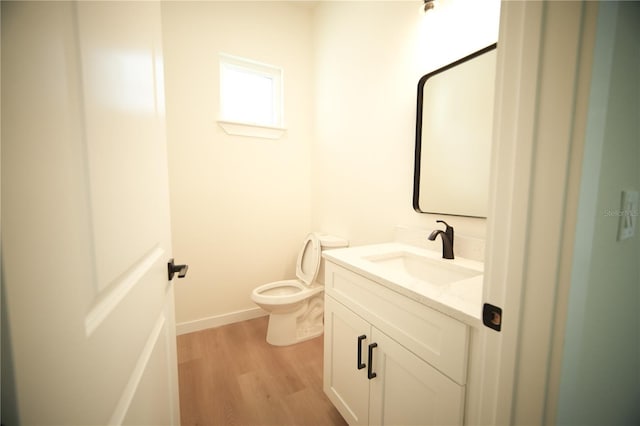 bathroom with wood-type flooring, toilet, and vanity