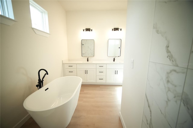 bathroom with vanity, a bath, and wood-type flooring