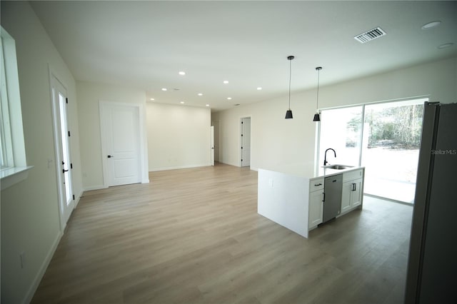 kitchen with light wood-type flooring, fridge, stainless steel dishwasher, pendant lighting, and white cabinets