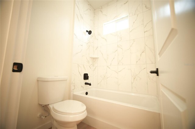 bathroom featuring tiled shower / bath combo and toilet