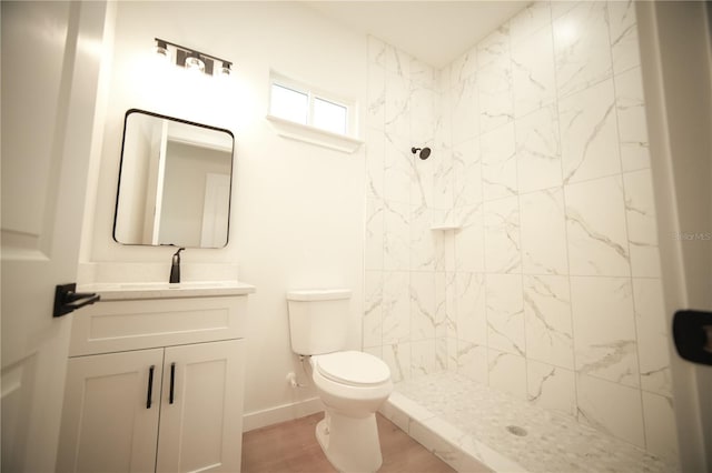 bathroom with hardwood / wood-style flooring, vanity, toilet, and a tile shower