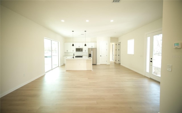 unfurnished living room featuring sink and light hardwood / wood-style floors