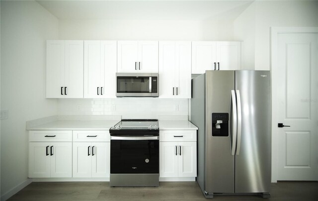 kitchen with dark wood-type flooring, stainless steel appliances, decorative backsplash, and white cabinets