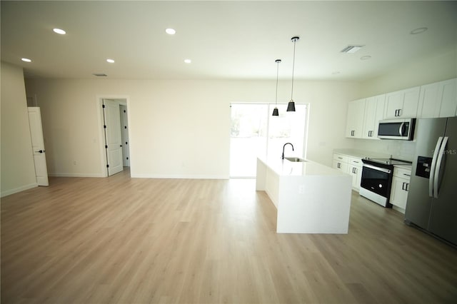 kitchen featuring appliances with stainless steel finishes, pendant lighting, white cabinetry, sink, and a kitchen island with sink