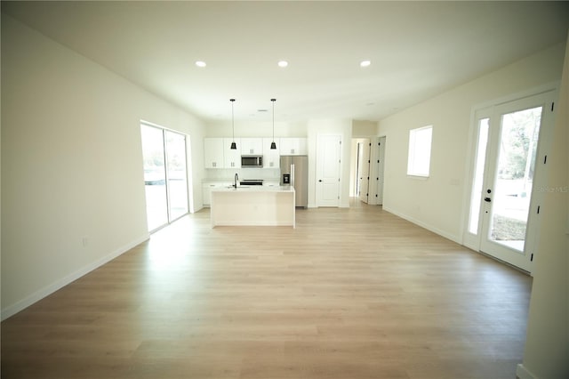 unfurnished living room with sink, a healthy amount of sunlight, and light wood-type flooring