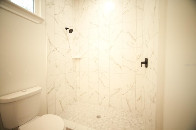 bathroom featuring tiled shower and toilet