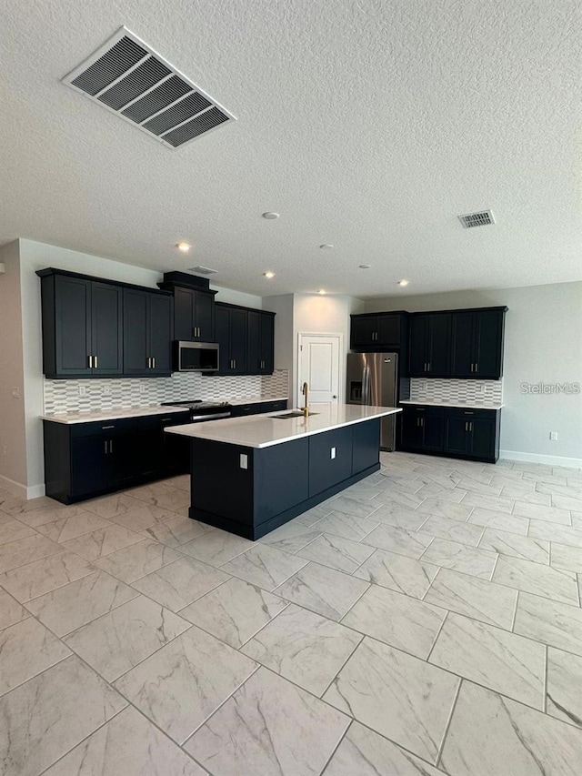 kitchen with stainless steel appliances, tasteful backsplash, a kitchen island with sink, and sink