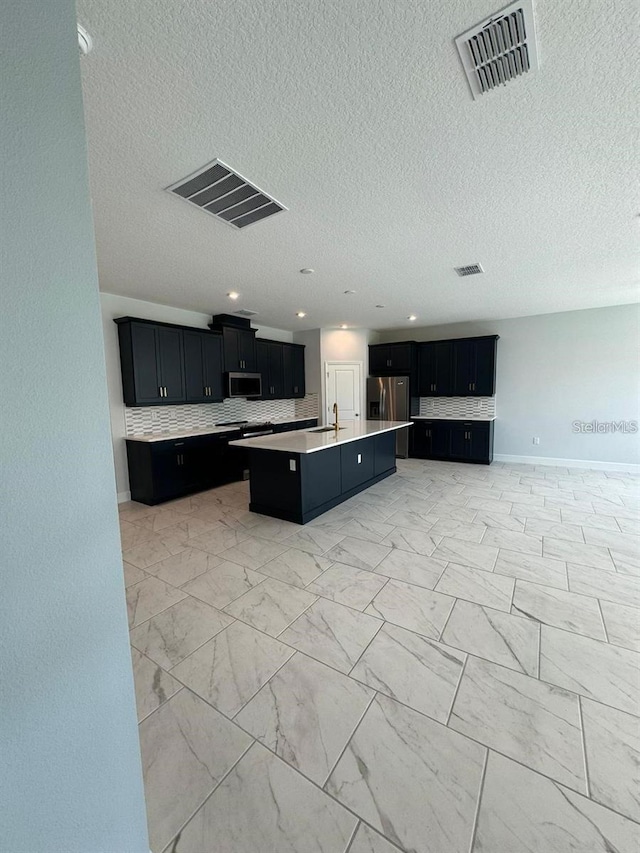 kitchen featuring tasteful backsplash, stainless steel appliances, sink, and a kitchen island with sink