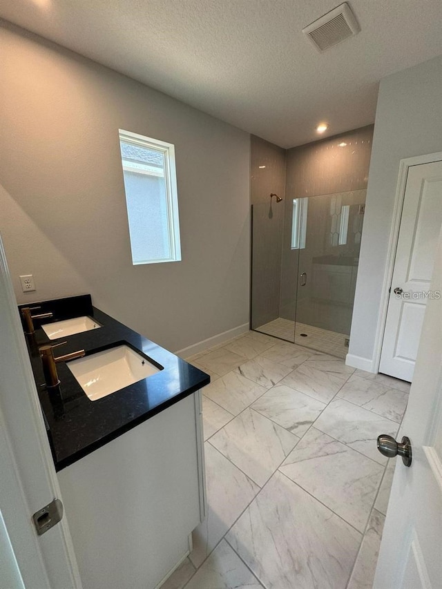 bathroom featuring vanity, an enclosed shower, and a textured ceiling