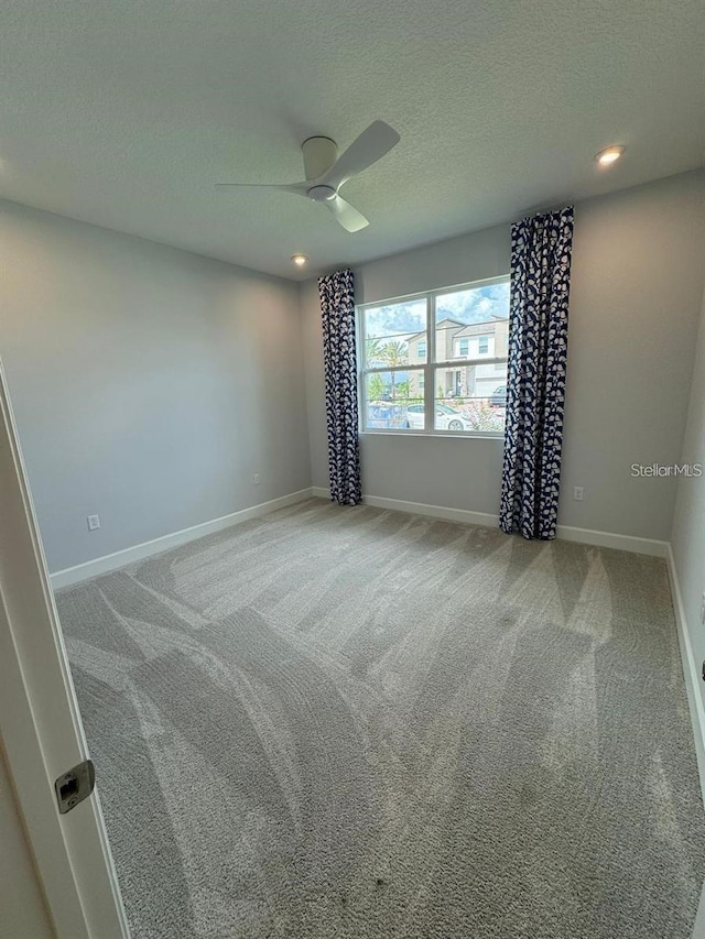 carpeted empty room with ceiling fan and a textured ceiling