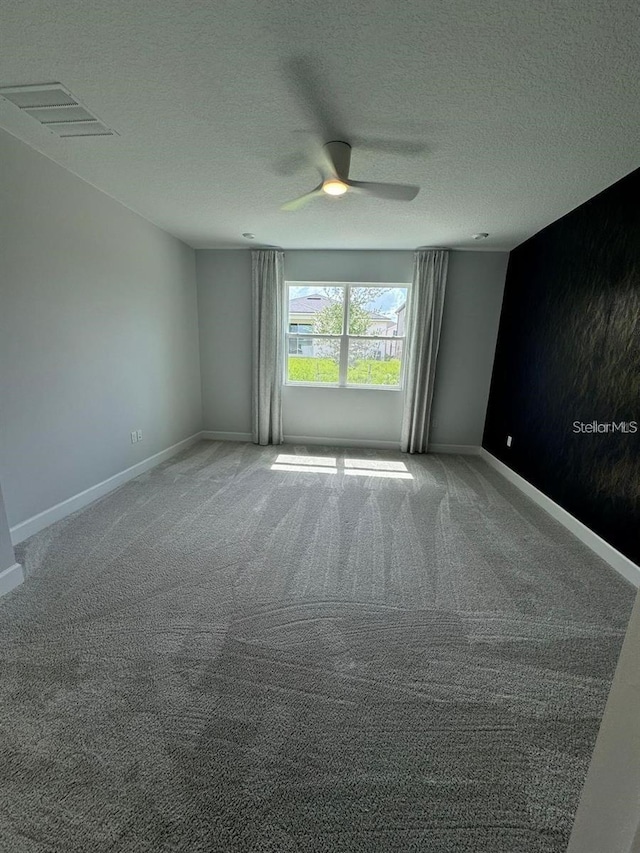 unfurnished room with ceiling fan, carpet, and a textured ceiling