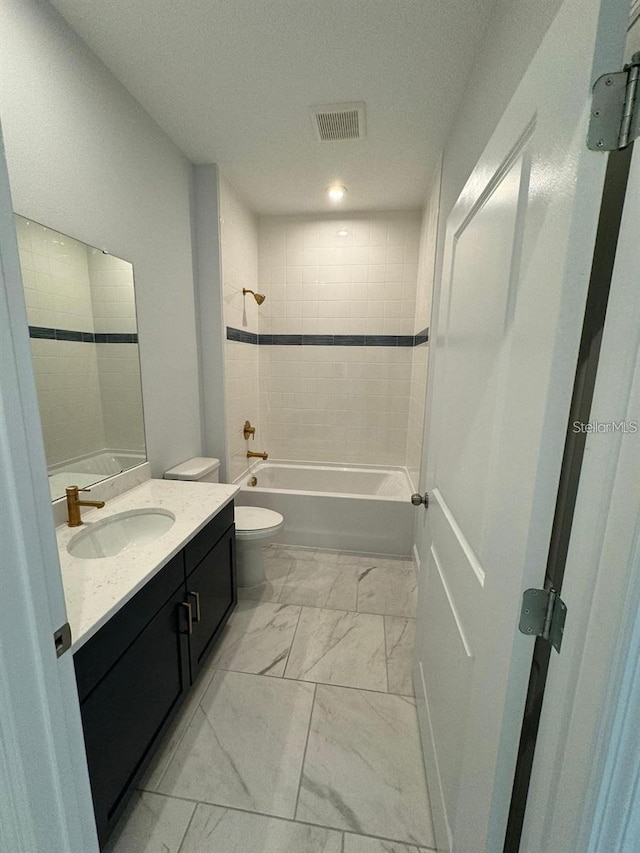 full bathroom with vanity, tiled shower / bath combo, and toilet