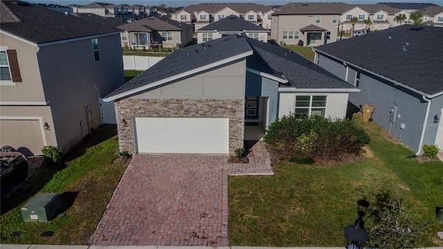 view of front of home featuring decorative driveway, stucco siding, a front yard, a residential view, and stone siding