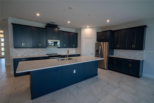 kitchen with a center island with sink, marble finish floor, stainless steel appliances, light countertops, and a sink