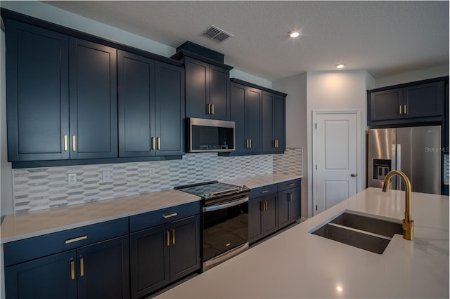 kitchen featuring tasteful backsplash, light countertops, visible vents, appliances with stainless steel finishes, and a sink