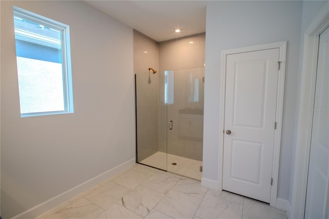 bathroom with marble finish floor, a shower stall, and baseboards