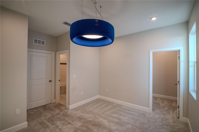 carpeted spare room featuring visible vents and baseboards