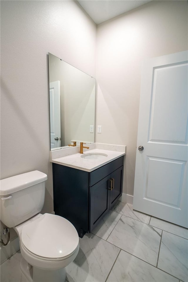 bathroom featuring toilet, marble finish floor, and vanity