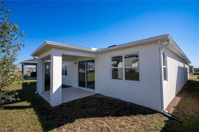 back of property with a patio area, a yard, and stucco siding