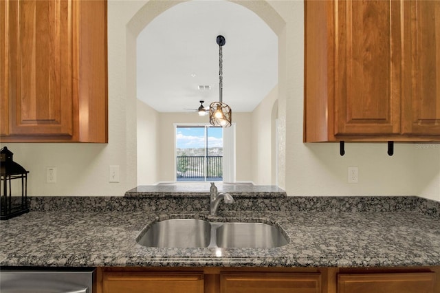 kitchen with dark stone countertops, sink, and pendant lighting