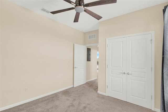 unfurnished bedroom featuring ceiling fan, light colored carpet, a closet, and electric panel