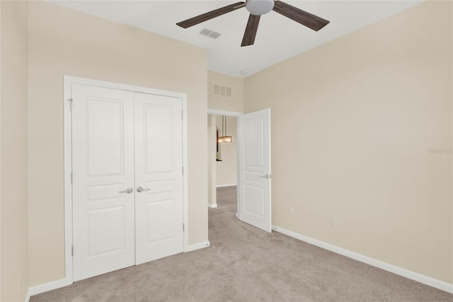 unfurnished bedroom with ceiling fan, light colored carpet, and a closet