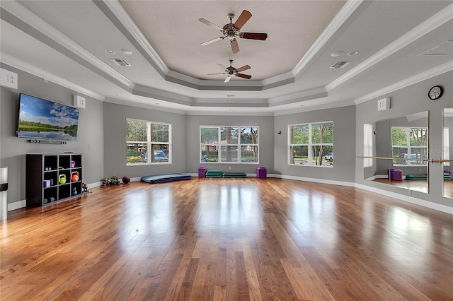 exercise room featuring hardwood / wood-style floors, crown molding, and a raised ceiling