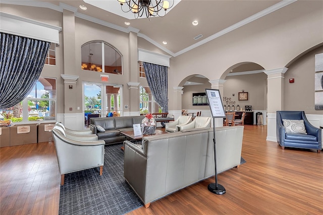 living room featuring ornamental molding, high vaulted ceiling, decorative columns, and hardwood / wood-style floors