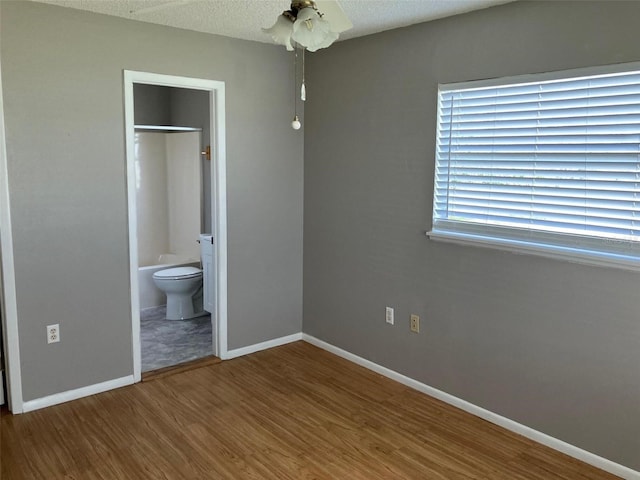 unfurnished bedroom featuring connected bathroom, hardwood / wood-style floors, and a textured ceiling