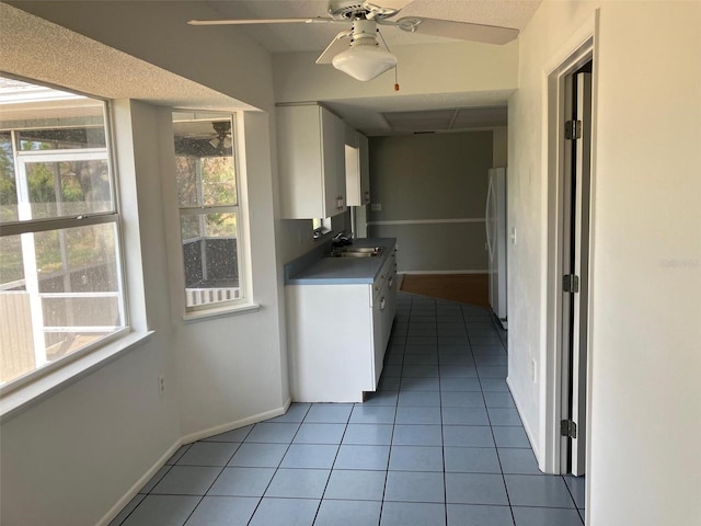 kitchen featuring sink, stainless steel fridge, ceiling fan, white cabinets, and light tile patterned flooring