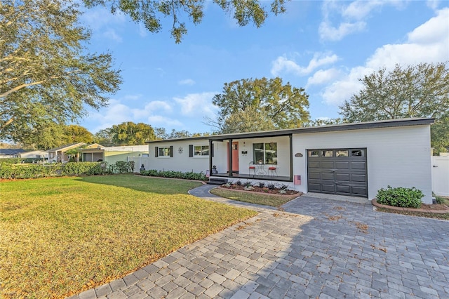 single story home with a garage, a front yard, and covered porch