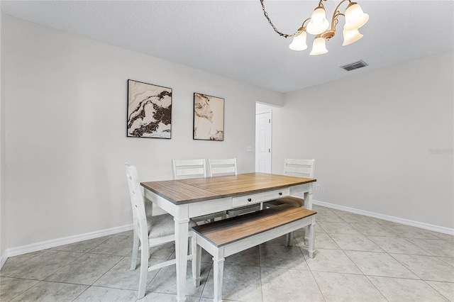 tiled dining room with a textured ceiling and a chandelier