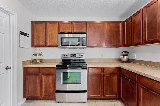 kitchen featuring stainless steel appliances, light tile patterned floors, and a textured ceiling