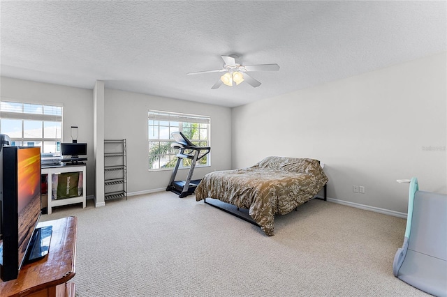 carpeted bedroom featuring ceiling fan and a textured ceiling