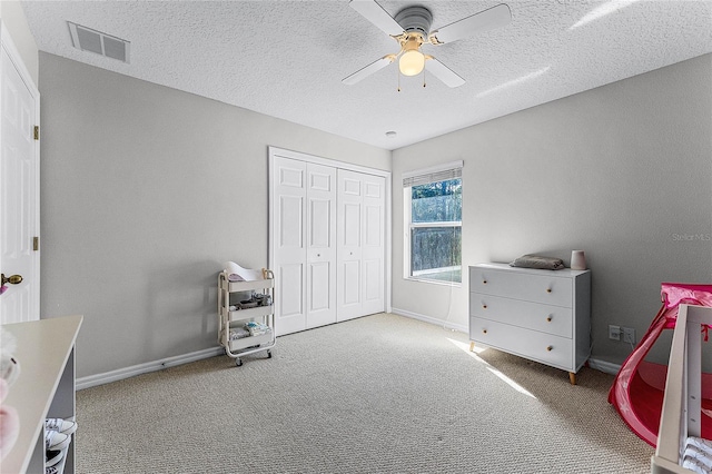 carpeted bedroom featuring ceiling fan, a textured ceiling, and a closet