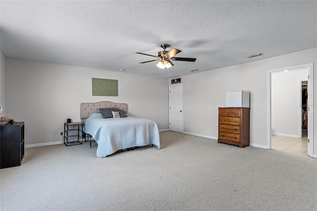 bedroom featuring ceiling fan, light colored carpet, refrigerator, and a textured ceiling