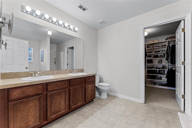 bathroom with an enclosed shower, vanity, a textured ceiling, tile patterned floors, and toilet