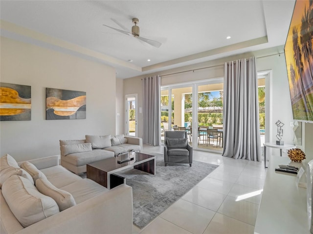 tiled living room with a tray ceiling and ceiling fan