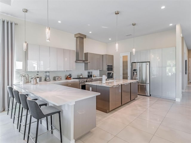 kitchen featuring a kitchen bar, ventilation hood, pendant lighting, stainless steel appliances, and backsplash