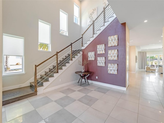 stairway with tile patterned flooring and a high ceiling