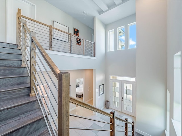 stairs with french doors, a towering ceiling, and tile patterned flooring