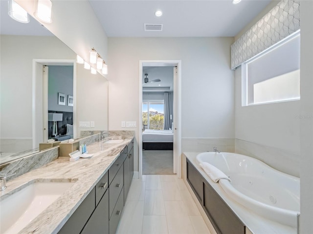 bathroom with a tub to relax in, vanity, and tile patterned floors