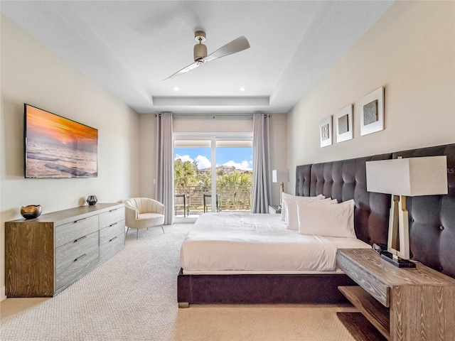 bedroom featuring ceiling fan, a tray ceiling, light carpet, and access to exterior