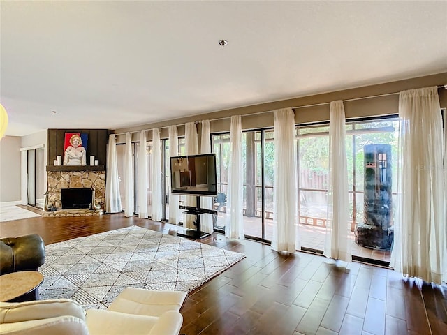 living room featuring a stone fireplace and dark hardwood / wood-style flooring