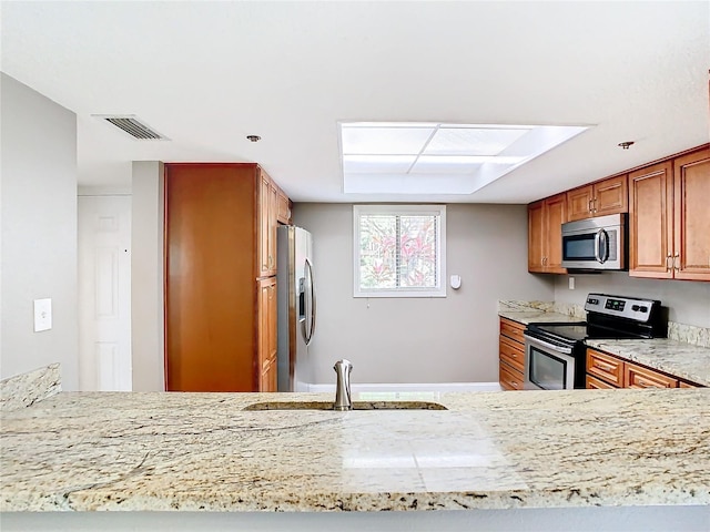 kitchen featuring appliances with stainless steel finishes, light stone countertops, sink, and kitchen peninsula