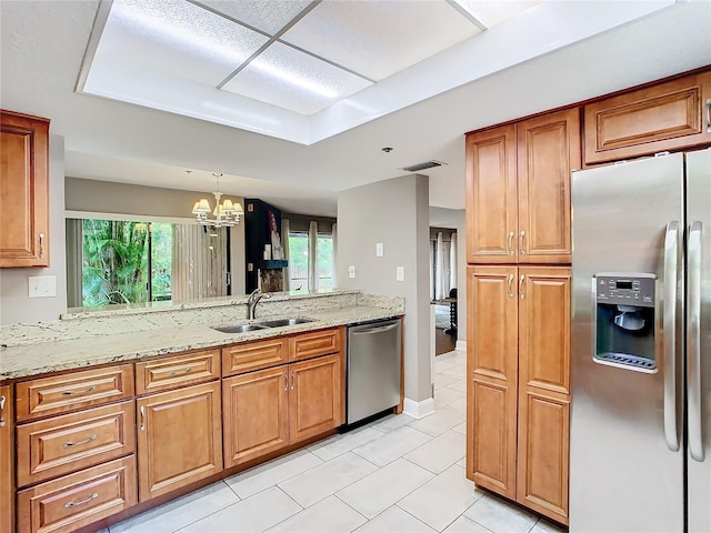 kitchen featuring sink, light stone counters, hanging light fixtures, a wealth of natural light, and stainless steel appliances